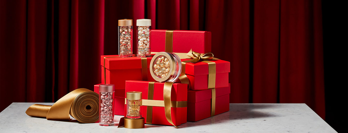 Red gift boxes with gold ribbons and decorative items on a red curtain background
