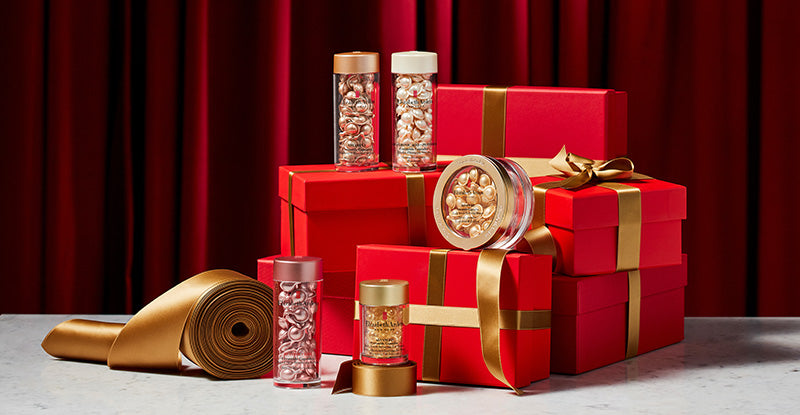 Red gift boxes with gold ribbons and decorative items on a red curtain background