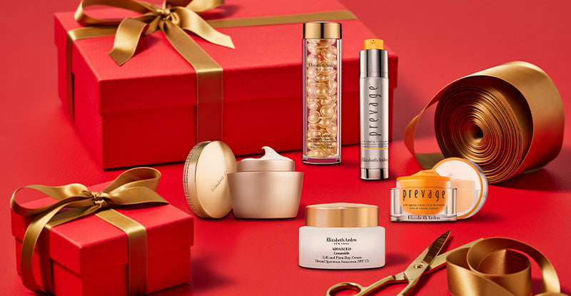 Red gift box with gold ribbon and decorative items on a red background featured with Elizabeth Arden Skincare products.