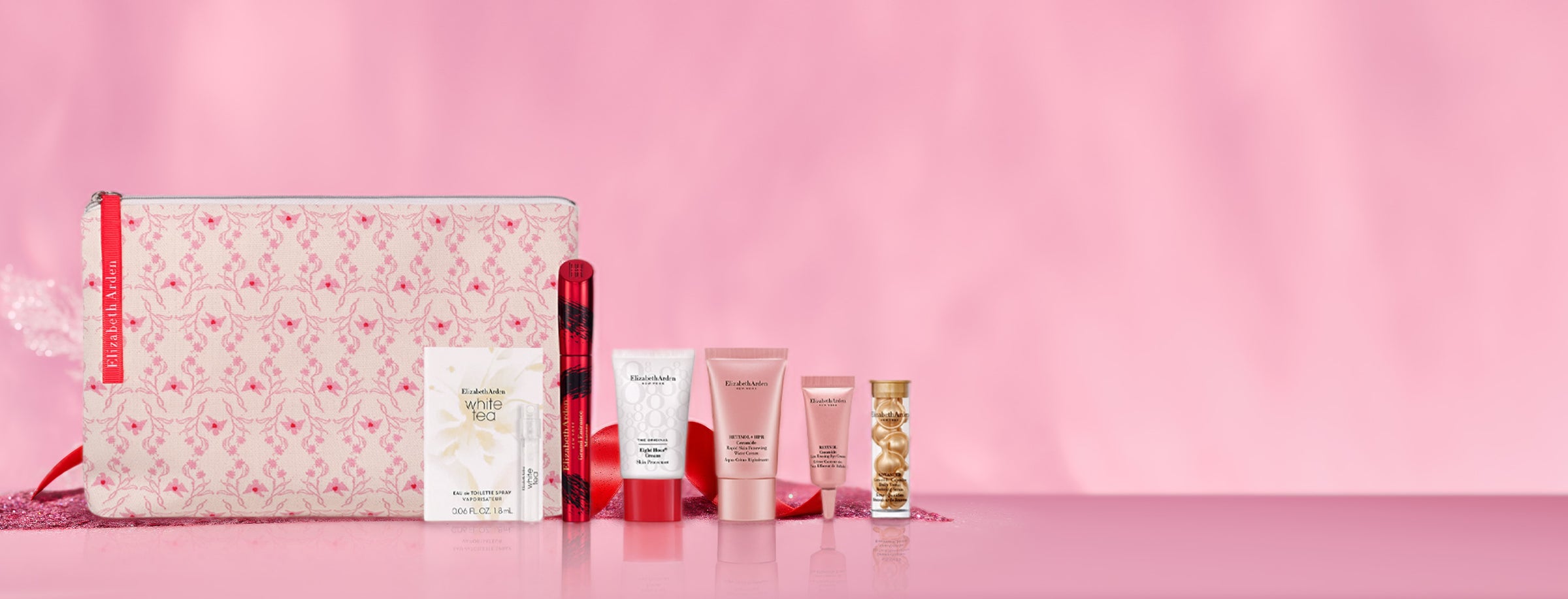 Set of skincare products and a pouch on a pink background