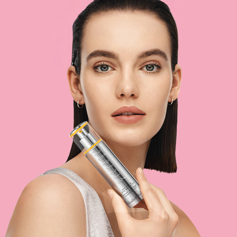 Woman holding a prevage skincare product against a pink background