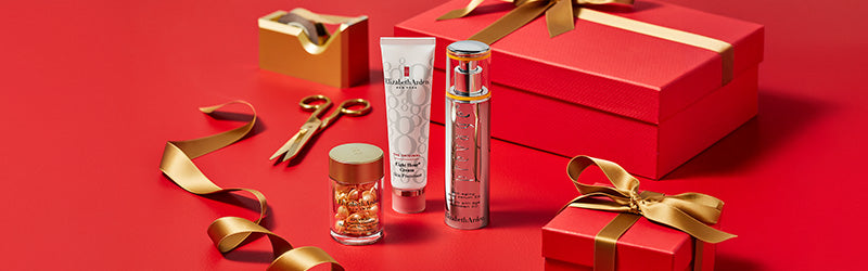 Elizabeth Arden skincare products featured with red gift boxes with gold ribbons and red accents on a red surface
