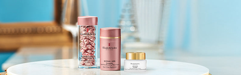 Elizabeth Arden skin care products on a marble table top with gold mirror in the background on a blue blue background