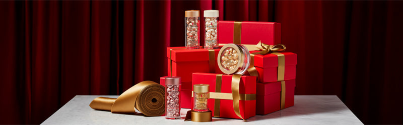 Elizabeth Arden Ceramide Capsules products on red gift boxes with gold ribbon featured along a deep red curtain back drop