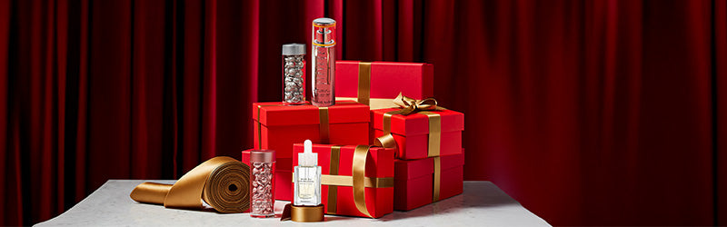 Elizabeth Arden Skin care products on red gift boxes with gold ribbon featured along a deep red curtain back drop