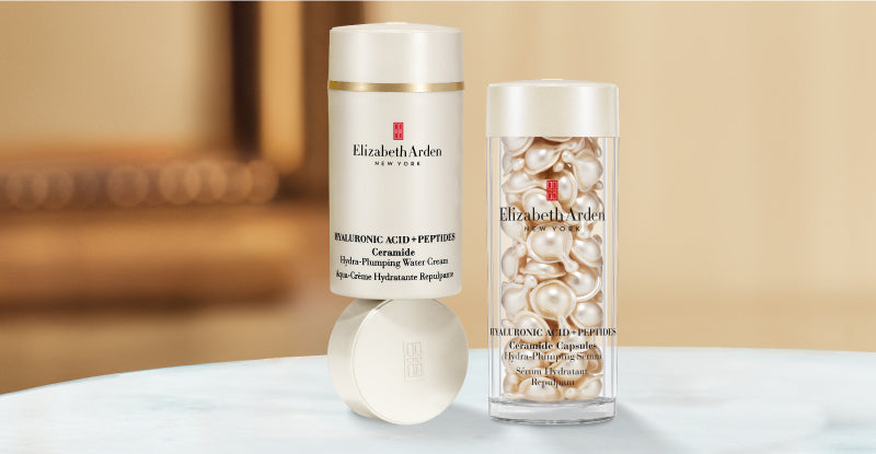 Collection of Elizabeth Arden Hyaluronic Acid + Peptides skincare products on a blurred beige background