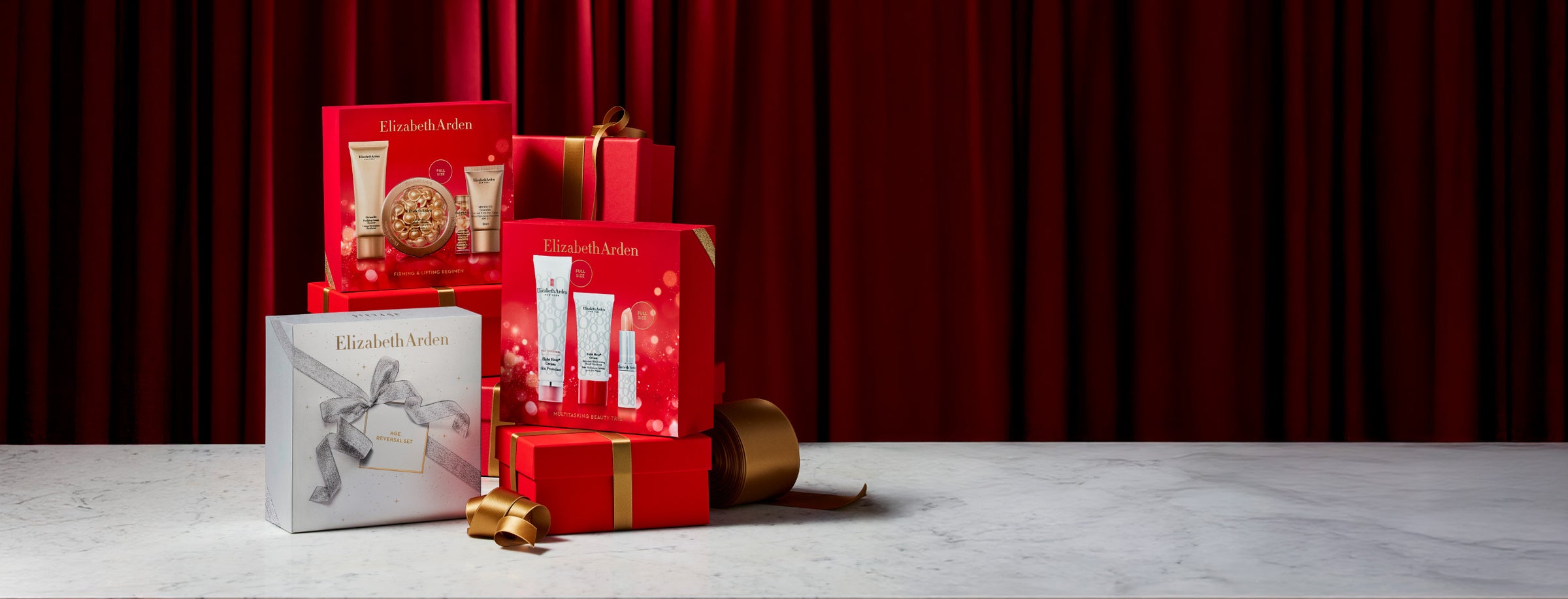 Elizabeth Arden gift set with red boxes and skincare products on a red curtain background