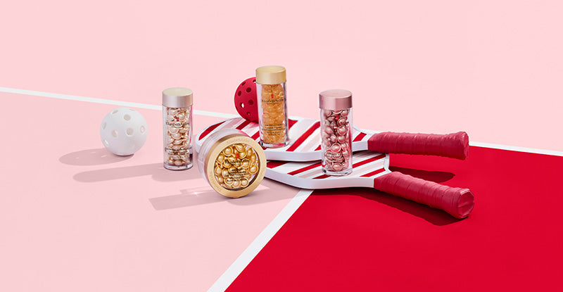 Elizabeth Arden Capsule Serum products on a pink and red background with pickleball paddles and balls.