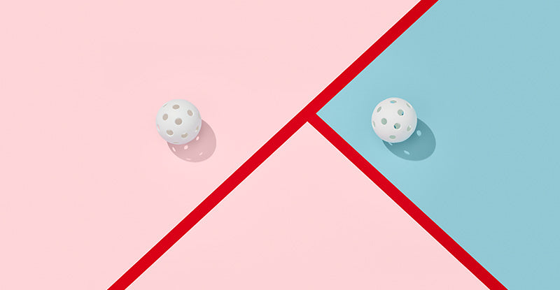 Two white balls on a pink, blue, and red geometric patterned background