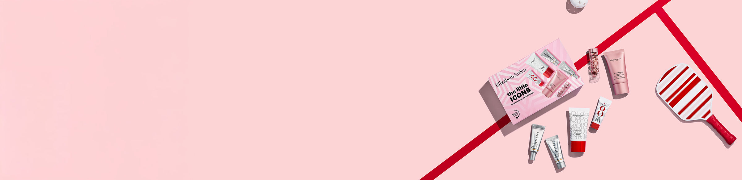 Elizabeth Arden skincare set laid flat on a   on a pink and red background next to a stripe pickleball paddle and ball