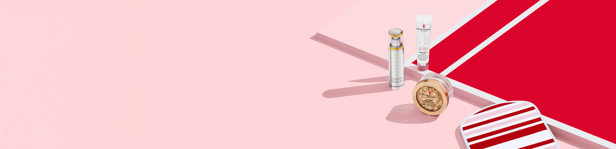 Collection of Elizabeth Arden products on a pink and red background next to a stripe pickleball paddle