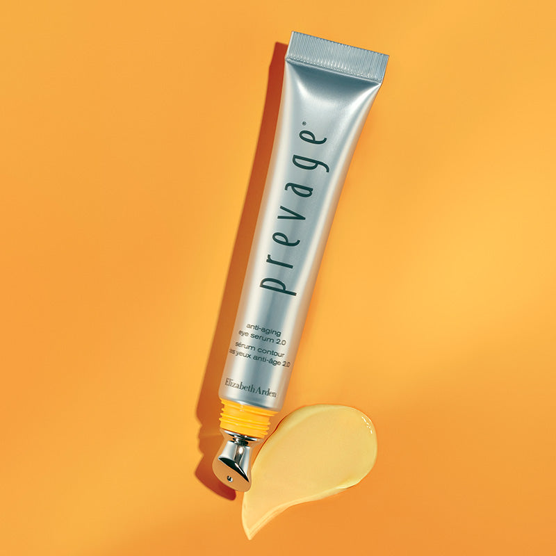 Prevage skincare tube with applicator and spill of product on an orange background