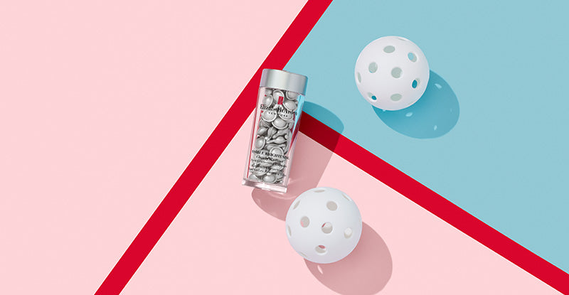 Two white balls next to Visible Brightening Clearly Radiant Spot Correcting Capsules on a pink and blue geometric background