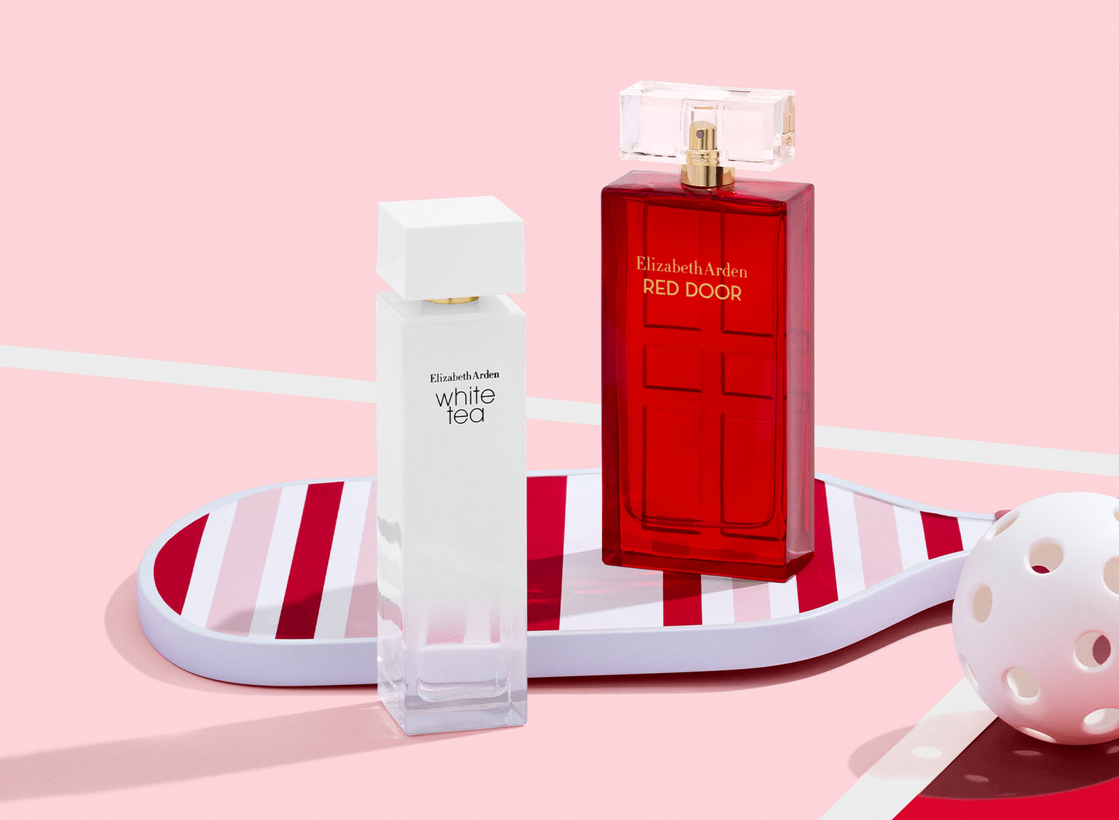 Two Elizabeth Arden perfume bottles, one white and one red, on a pink background.