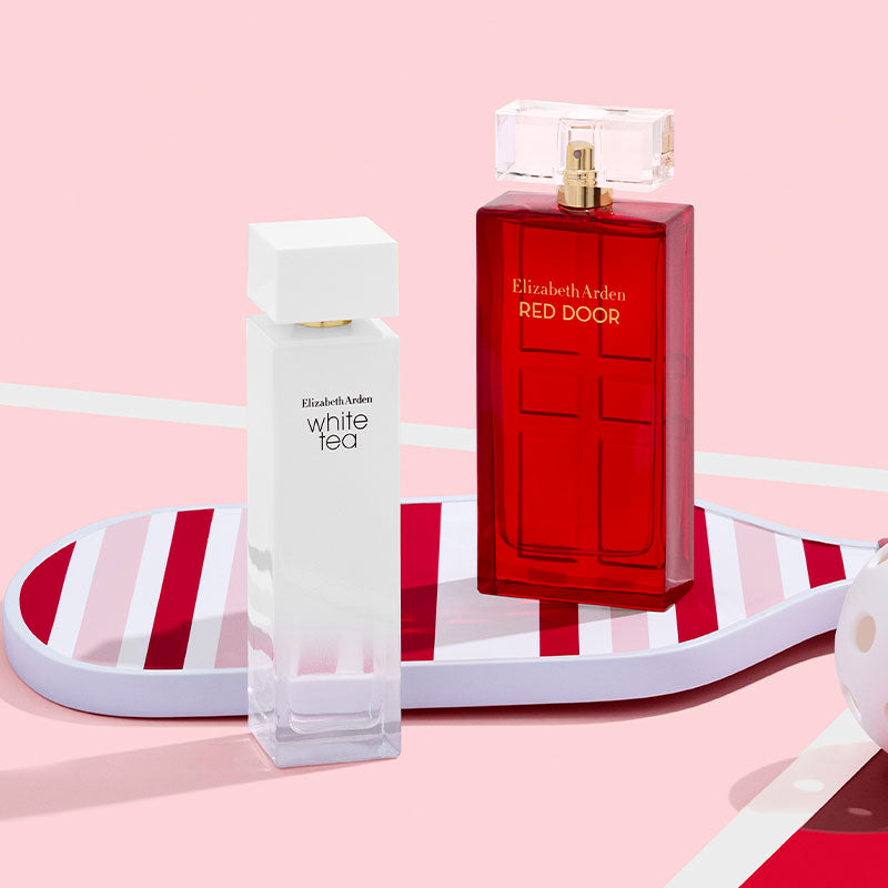 Two Elizabeth Arden perfume bottles, one white and one red, on a pink background.