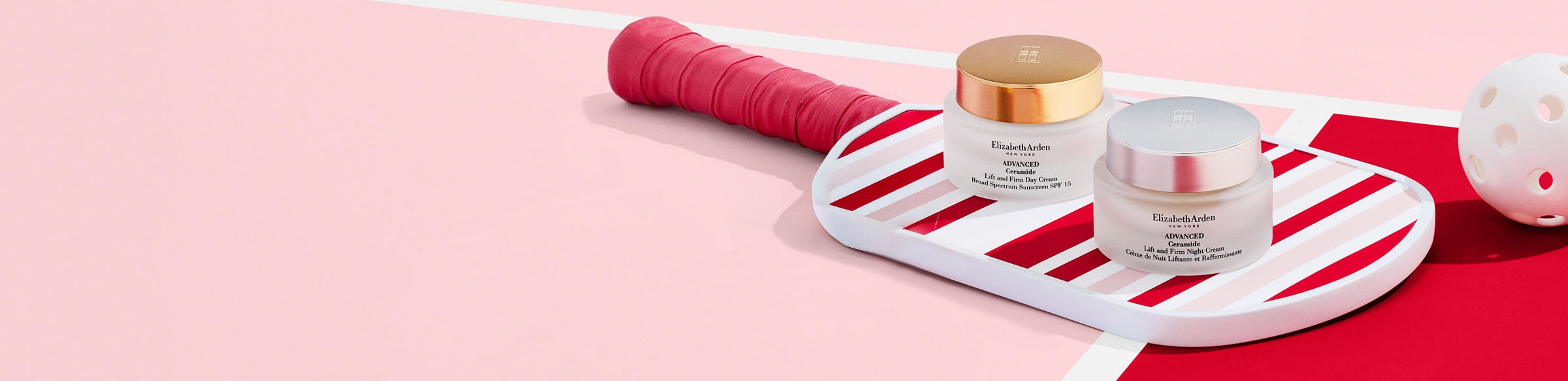Two skincare jars on a white tray with a pink and red striped background