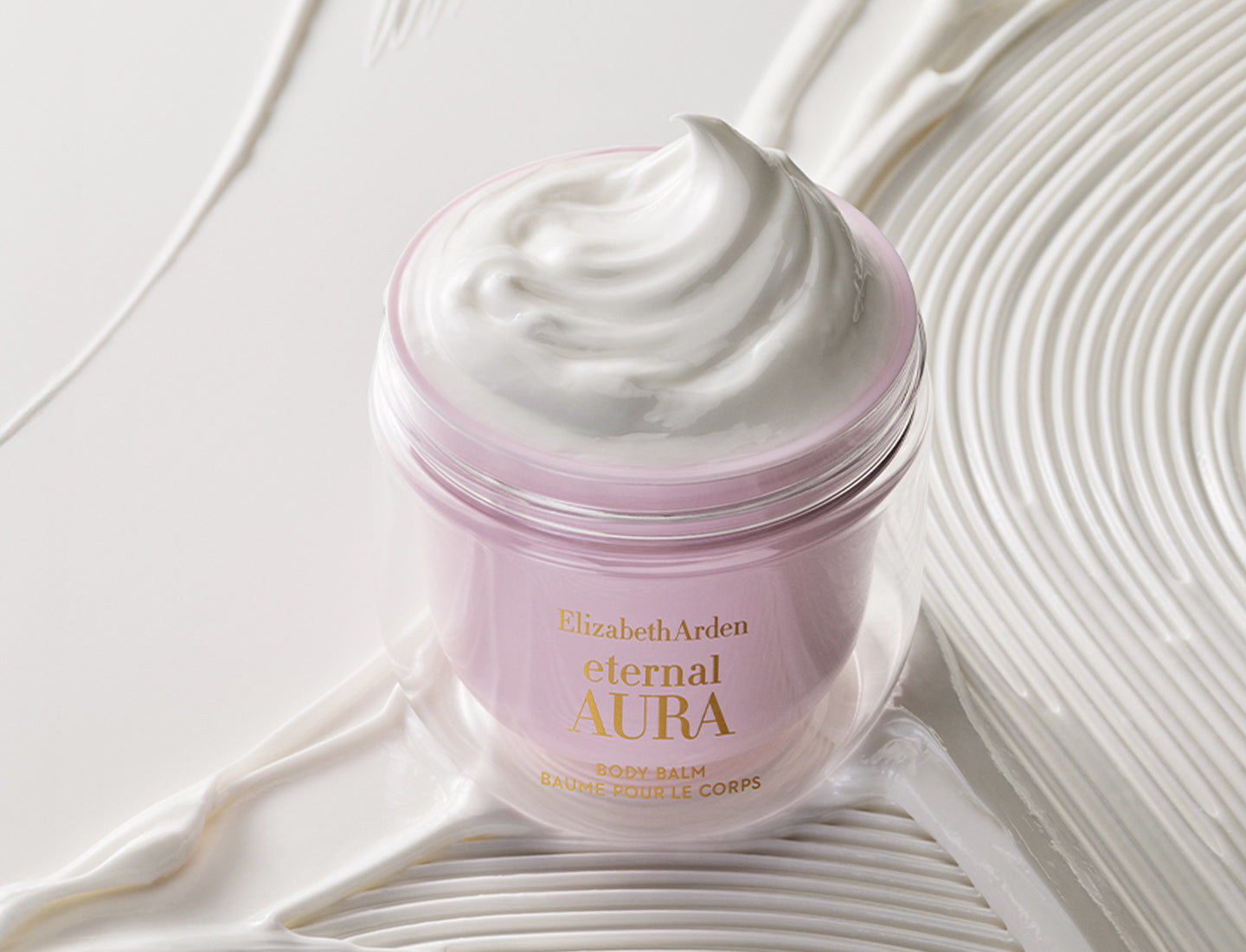 Pink jar of Elizabeth Arden Eternal Aura body balm on a textured white background