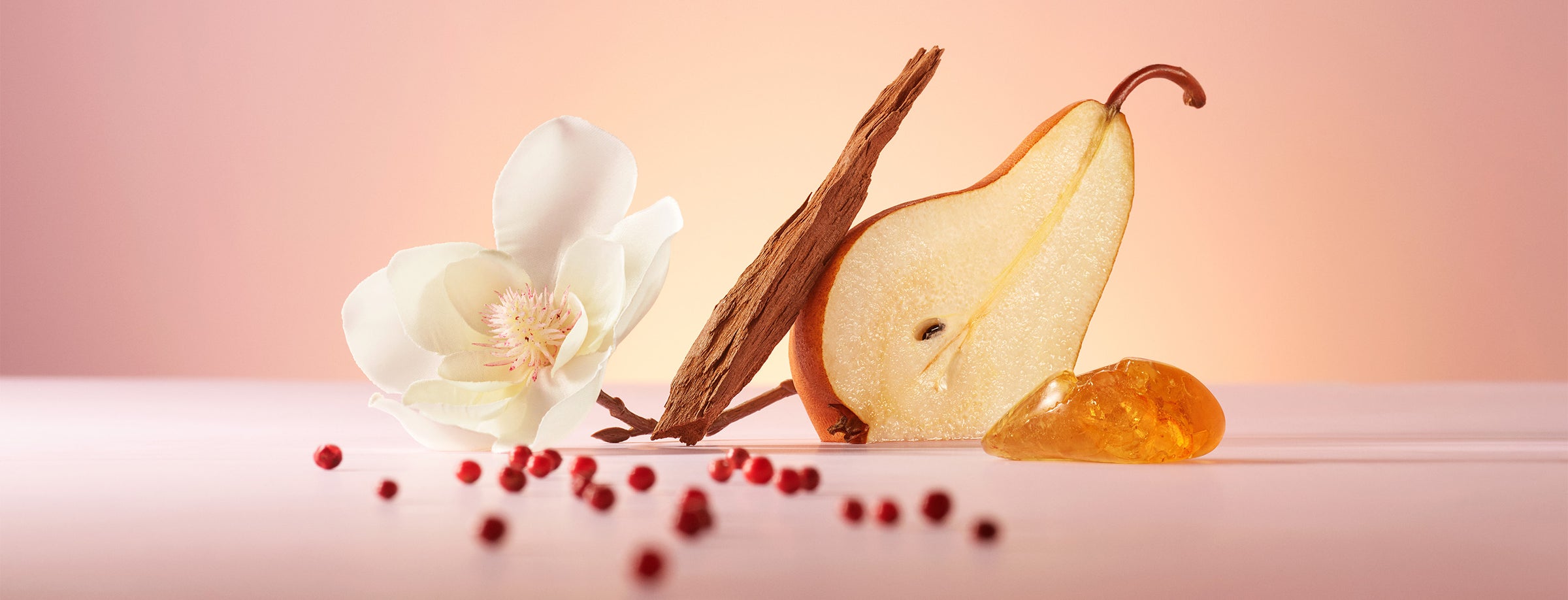 White magnolia flower, sandalwood, golden pear and pink pepper on a pink background