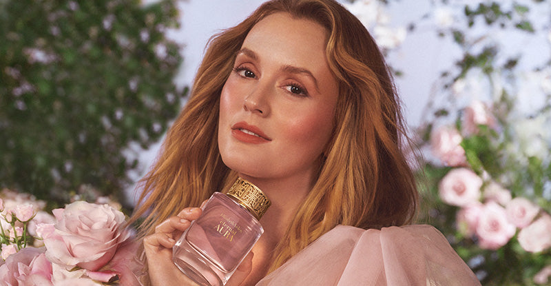 Female Celebrity holding Elizabeth Arden Eternal Aura perfume bottle with flowers in the background