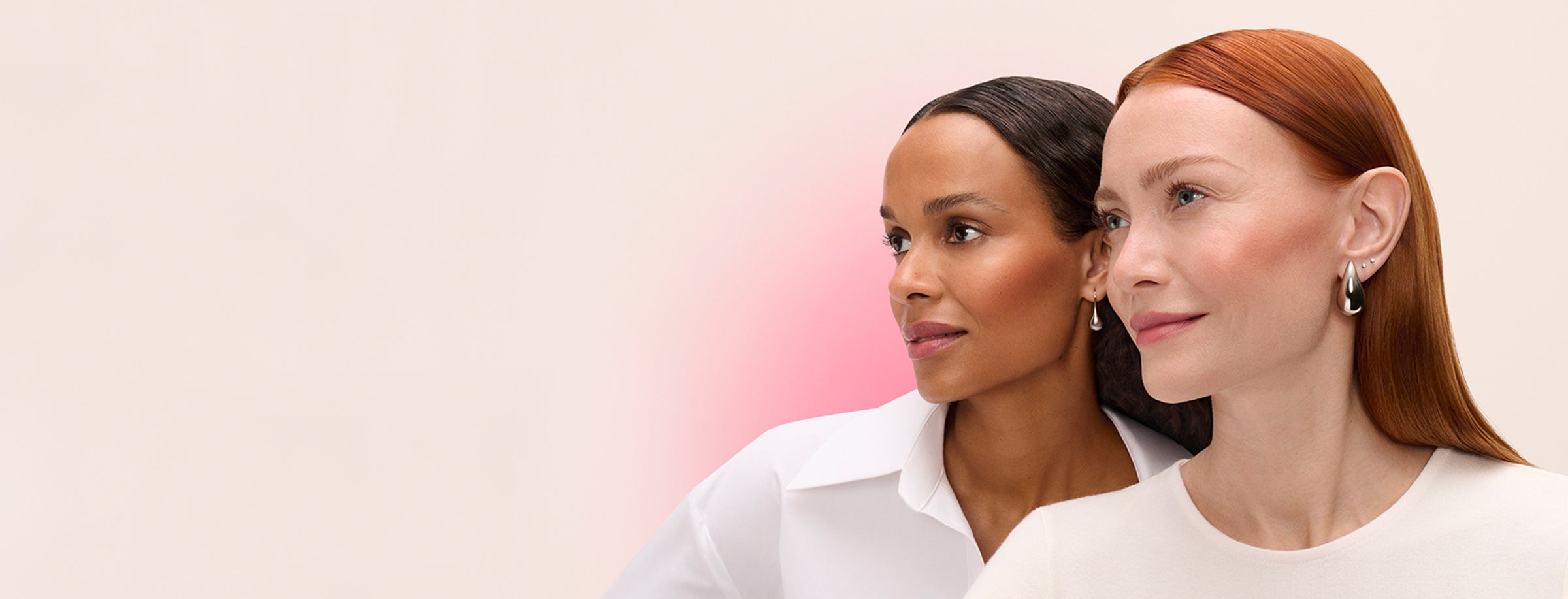 Two women standing side by side against a light pink background