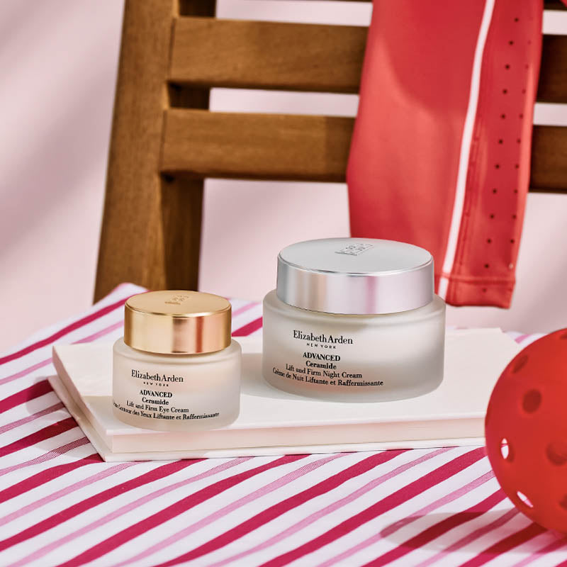Two jars of Elizabeth Arden cream on a striped surface with a chair and red object in the background.