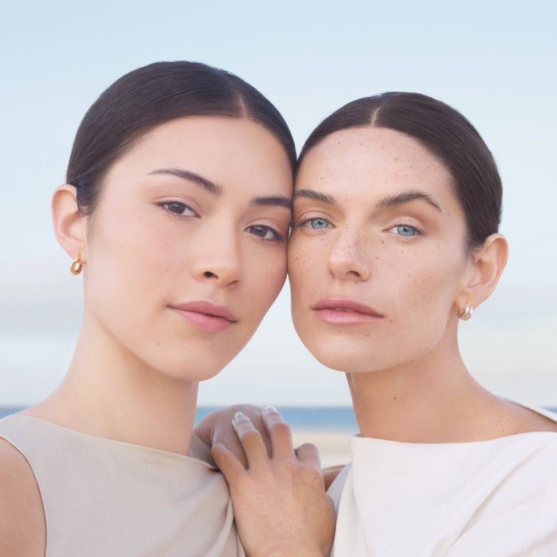 Two women standing close together with a light blue background