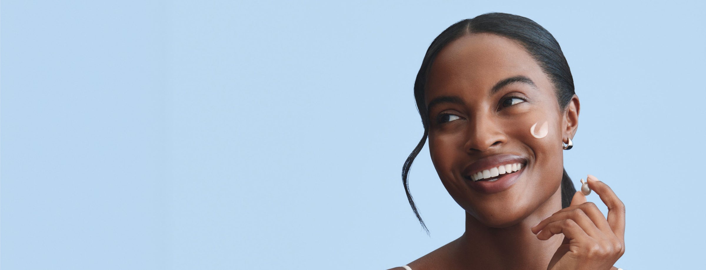 Woman with skincare product on her face with a blue background