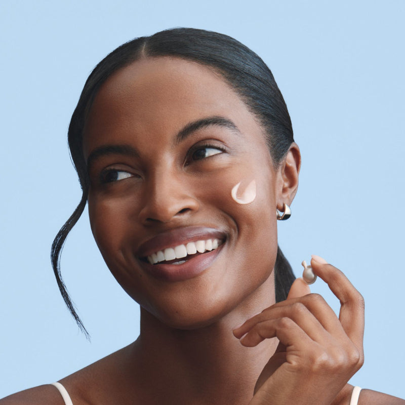 Woman with skincare product on her face with a blue background
