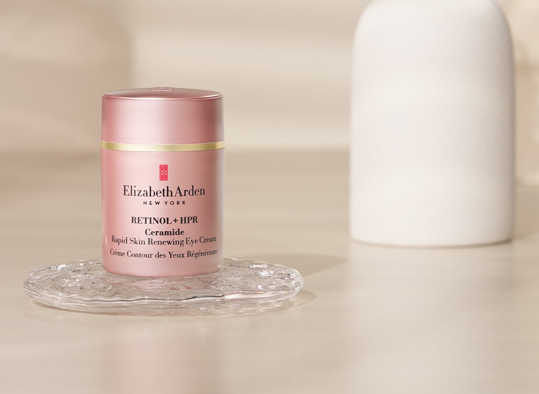 Elizabeth Arden Retinol + HPR Ceramide Eye Cream sitting on a clear tray on a beige background.