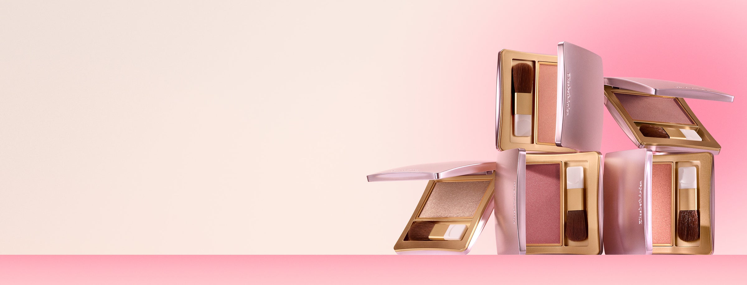 Makeup products including blushes and brushes on a pink background