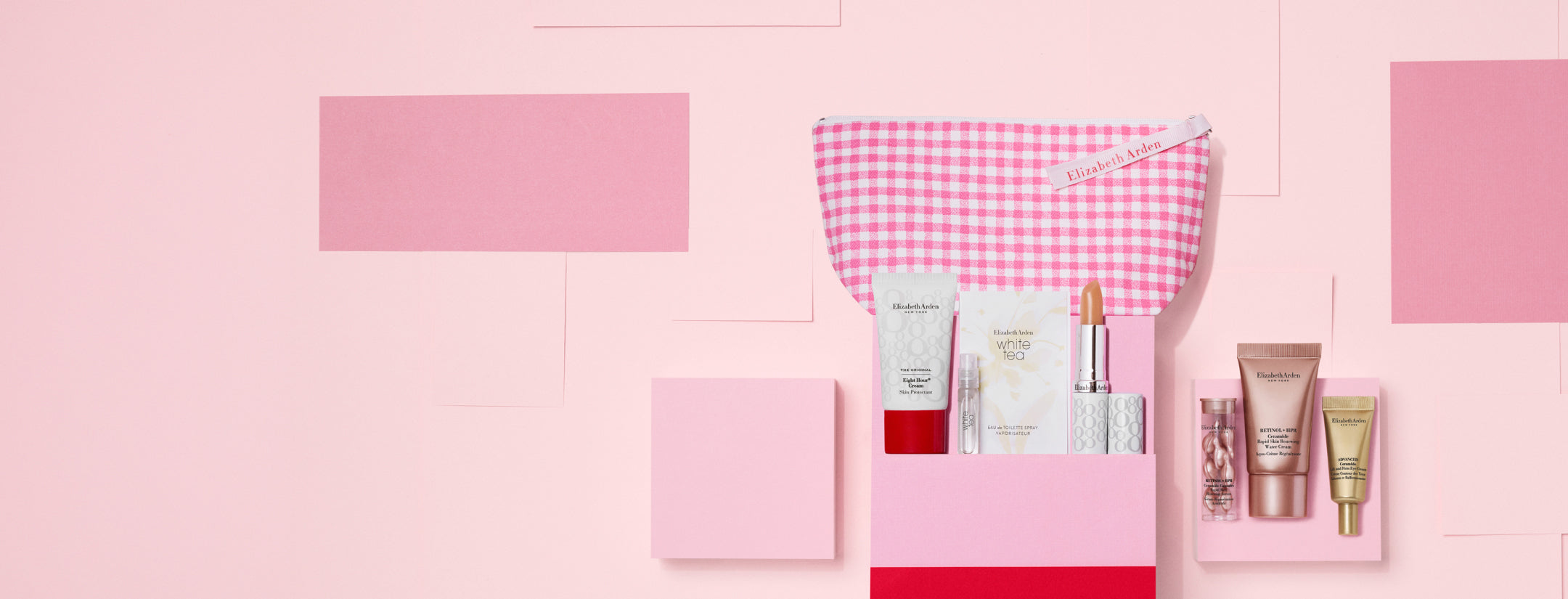 7-piece gift with purchase featuring 6 beauty products and a cosmetic bag on a pink wall