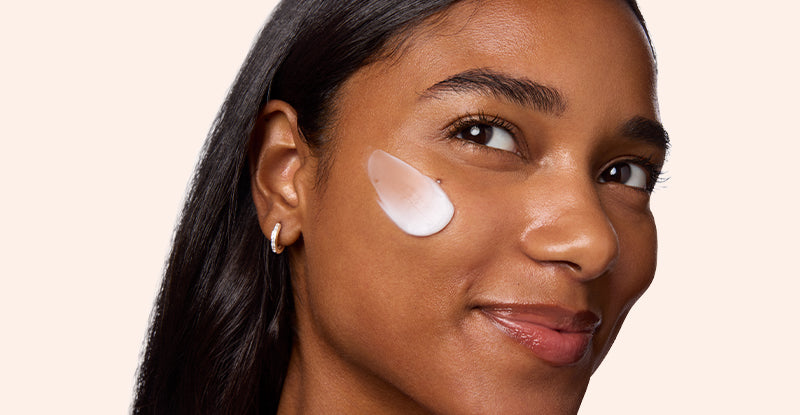Woman with a skincare product applied to her face on a beige background