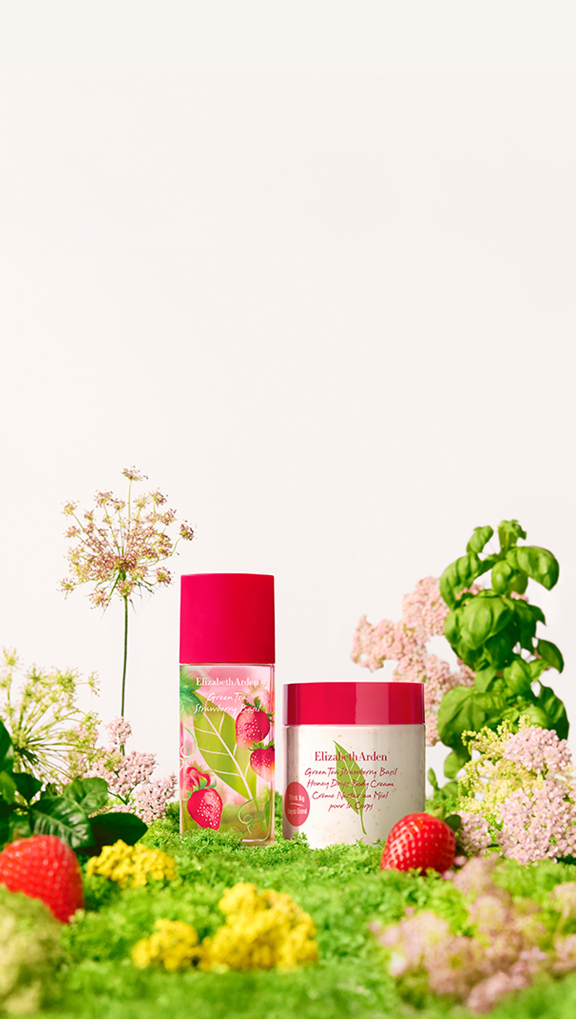 Elizabeth Arden Strawberry Basil collection products on in a bed of gren grass, plants, pink and yellow flowers and strawberries.
