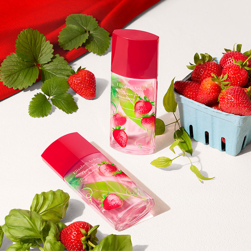 Two bottles of Elizabeth Arden Strawberry fragrance with strawberries and leaves on a white background