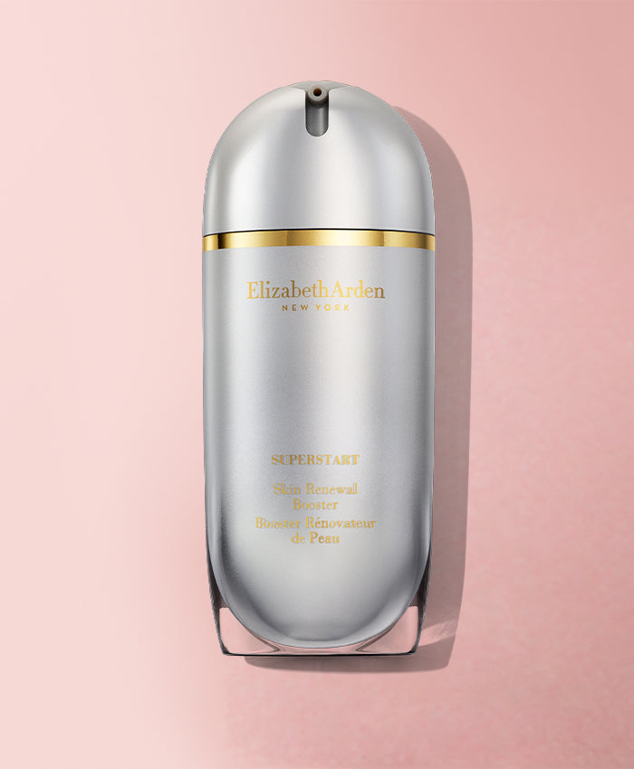 Elizabeth Arden Superstart Skin Renewal Booster in a sleek, metallic silver bottle with gold lettering and a gold accent band, set against a soft pink background.