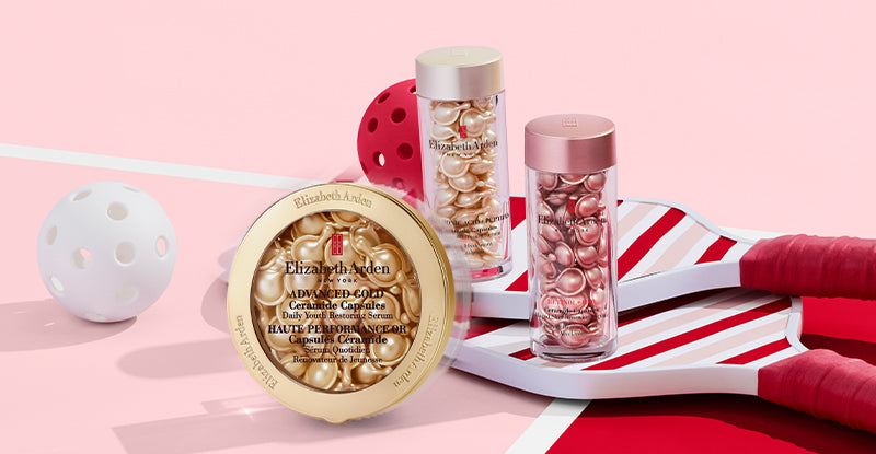 Elizabeth Arden Ceramide Capsules — Advanced Gold Ceramide Capsules Serum, Hyaluronic Acid + Peptides Ceramide Capsules Serum and Retinol + HPR Ceramide Capsules Serum on top of paddles on a pink and red background