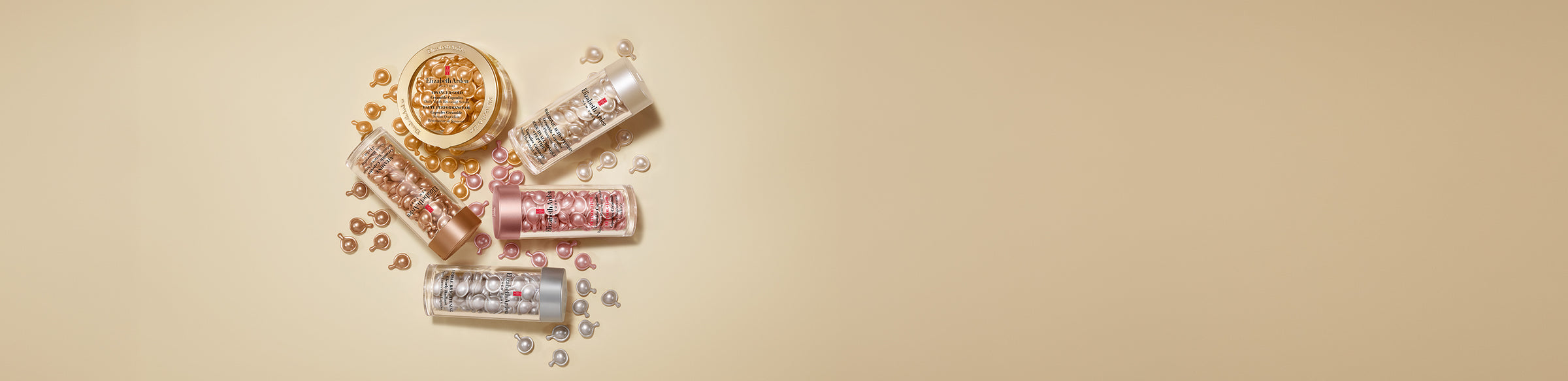 A styled flat-lay of Elizabeth Arden Capsules Serums with capsules spilling arranged on a warm beige background.