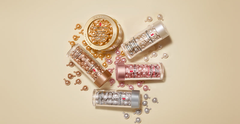 A styled flat-lay of Elizabeth Arden Capsules Serums with capsules spilling arranged on a warm beige background.