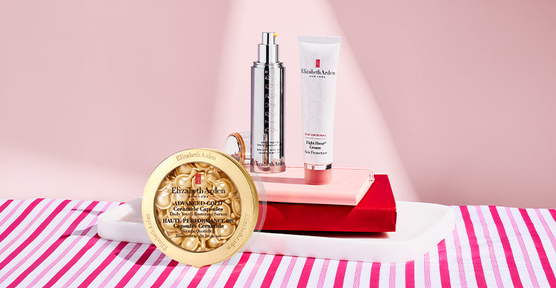 Elizabeth Arden Prevage Anti-aging 2.0 serum, Advanced Gold Ceramide Capsules Serum and Eight Hour Skin Protectant sitting on top of books on a pink background. 