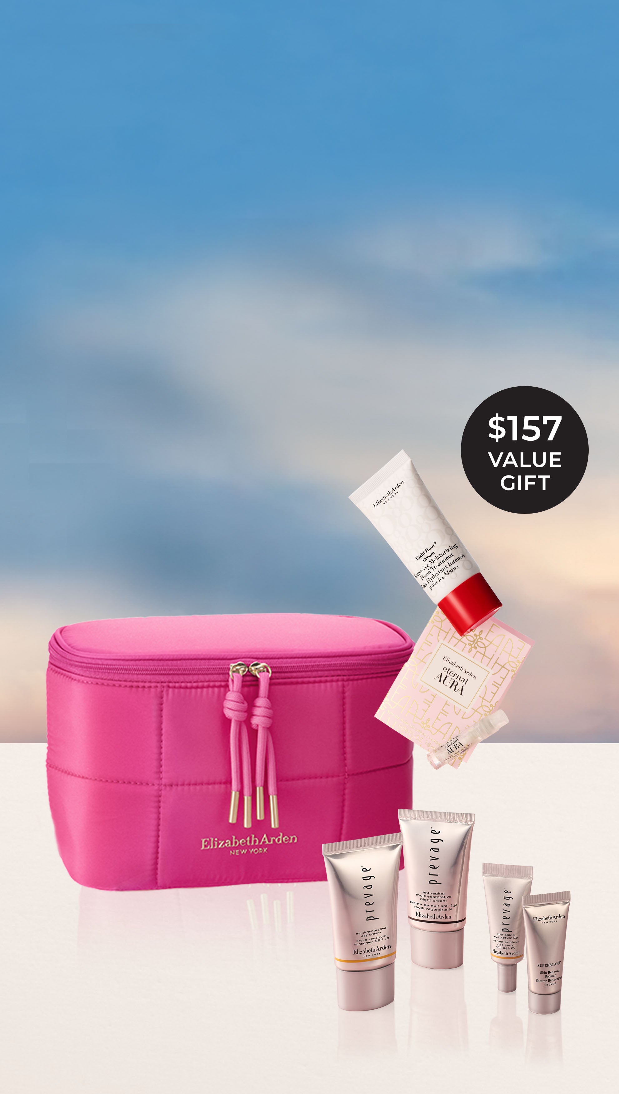 Elizabeth Arden gift with purchase set featuring a bright pink puffer zippered vanity bag with pink tassel zipper pulls, surrounded by 4 Prevage Mini products  and a mini Eight Hour Hand treatment and sample of Eternal Aura eau de parfum falling from above. They stand before a blue sky background, on a off white ledge with a black circular badge in the top right corner reads '$157 VALUE GIFT'.