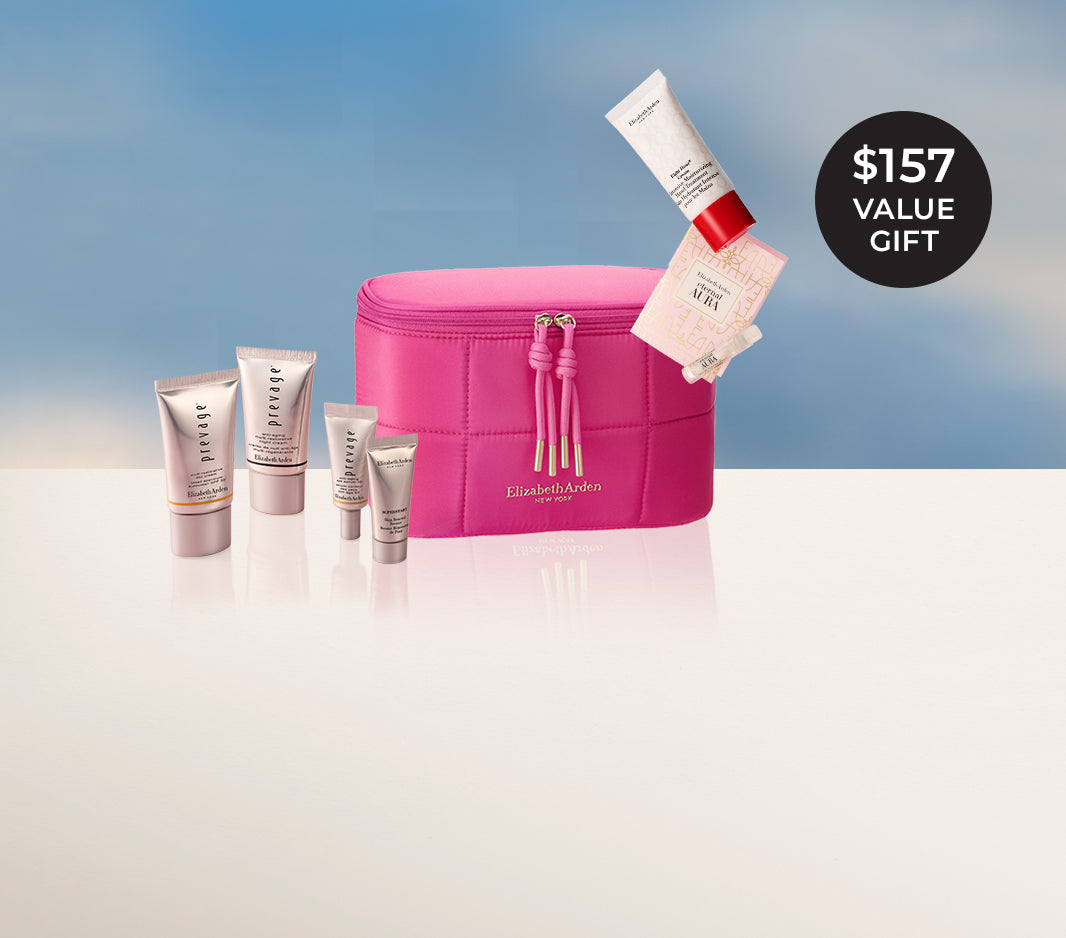 Elizabeth Arden gift with purchase set featuring a bright pink puffer zippered vanity bag with pink tassel zipper pulls, surrounded by 4 Prevage Mini products  and a mini Eight Hour Hand treatment and sample of Eternal Aura eau de parfum falling from above. They stand before a blue sky background, on a off white ledge with a black circular badge in the top right corner reads '$157 VALUE GIFT'.