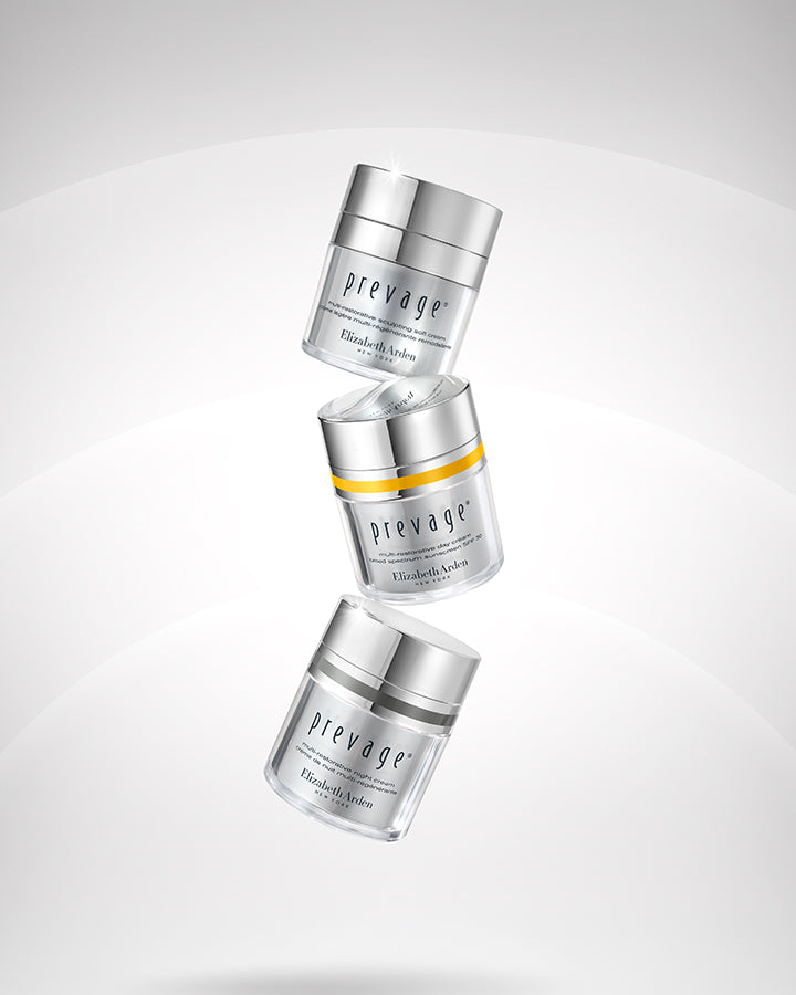 Three Prevage Elizabeth LaRoche skincare jars floating vertically on a light gray gradient background. The top and bottom jars are clear with silver lids, while the middle jar is clear with a silver lid and a yellow band.