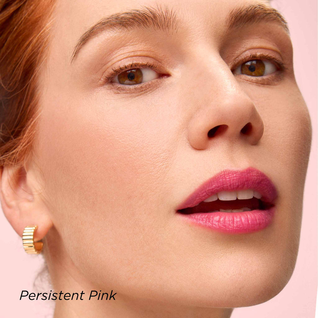 Close-up of a woman's face with pink lipstick in the shade Persistent Pink on a pink background