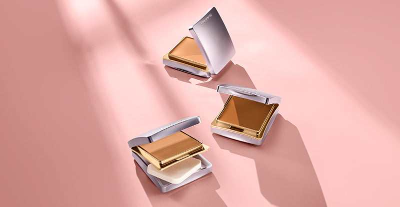 Three compact powder cases on a pink background