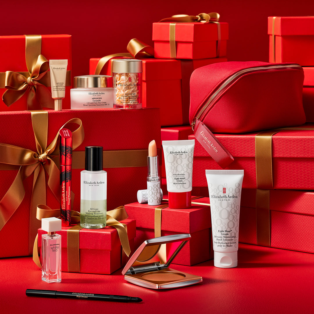 Cosmetic products and red gift boxes with gold ribbons on a red background