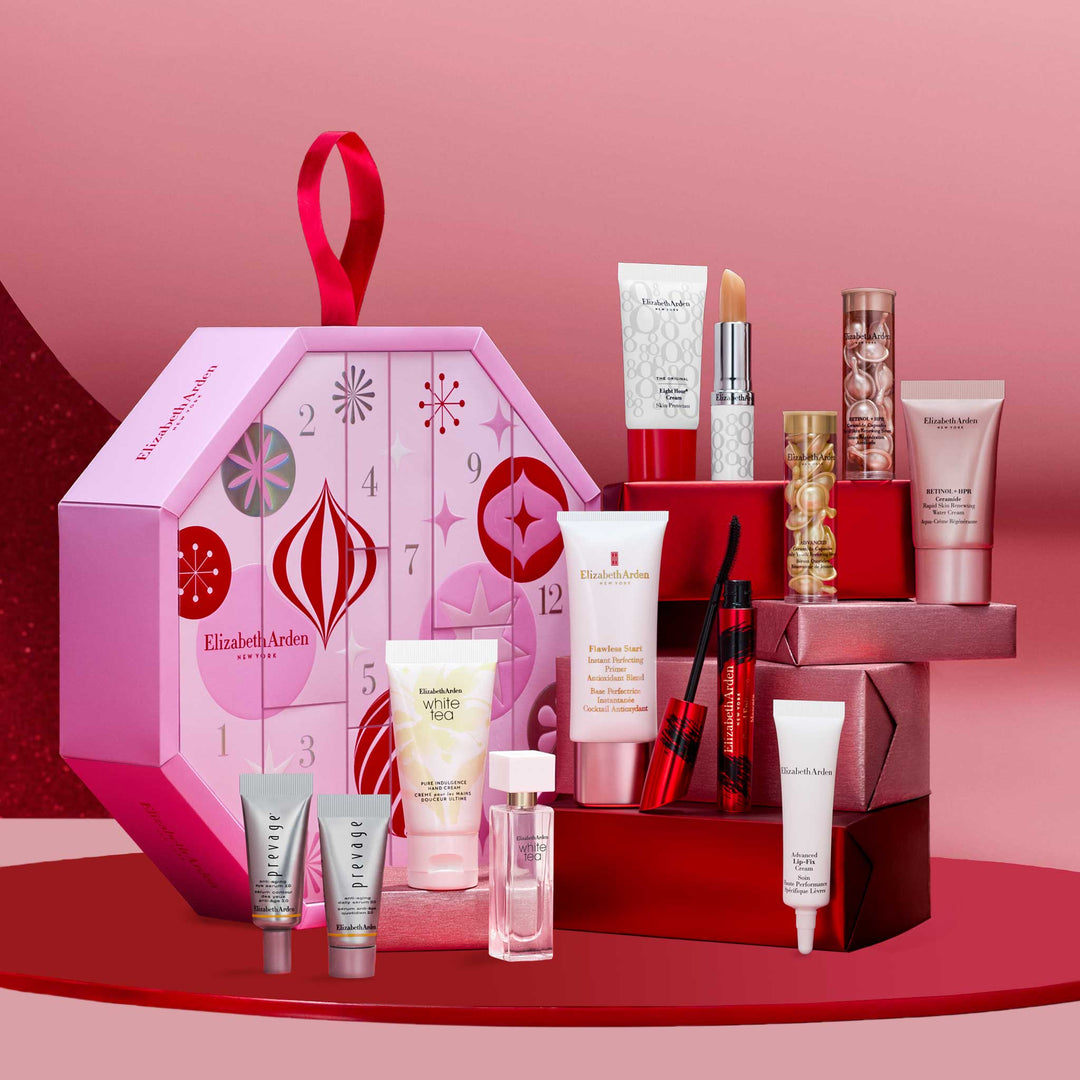 The pink Elizabeth Arden beauty advent calendar box with its skincare, makeup and fragrance products arranged on red pedestals against a dark red backdrop
