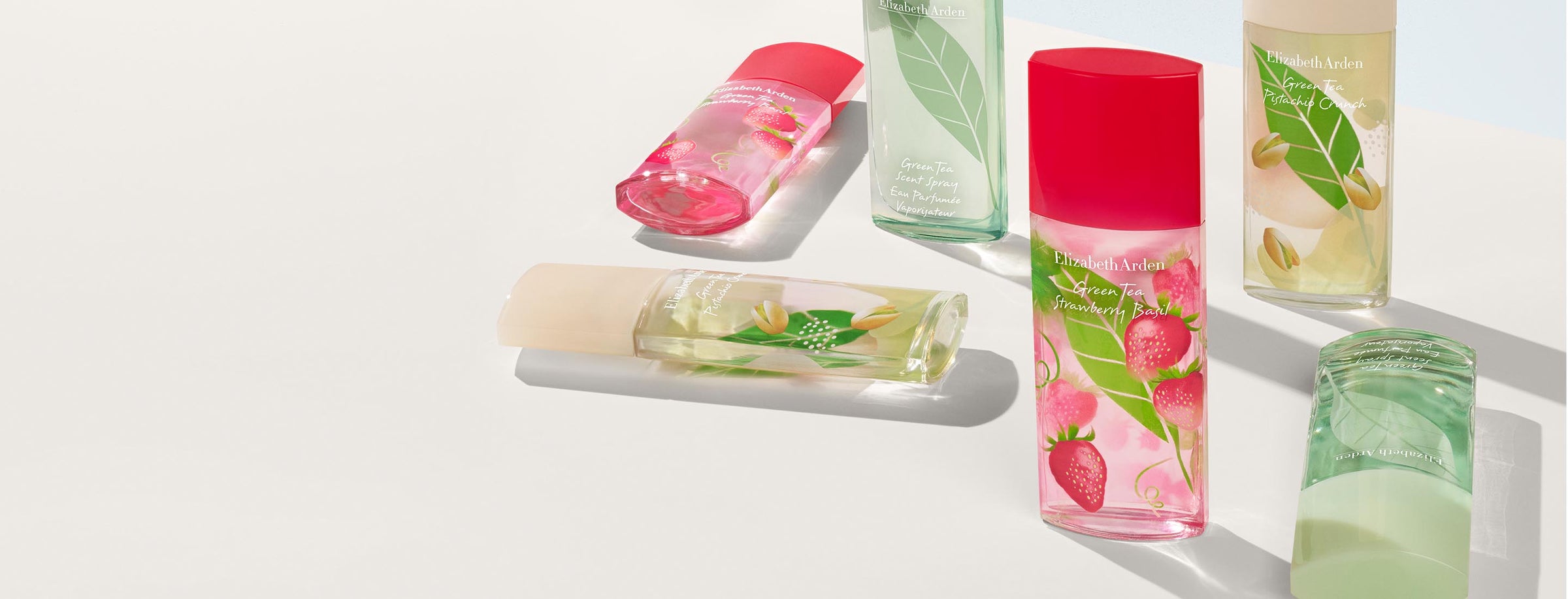 Green Tea fragrance bottles in original, pistachio, and strawberry basil scents styled on a light background.