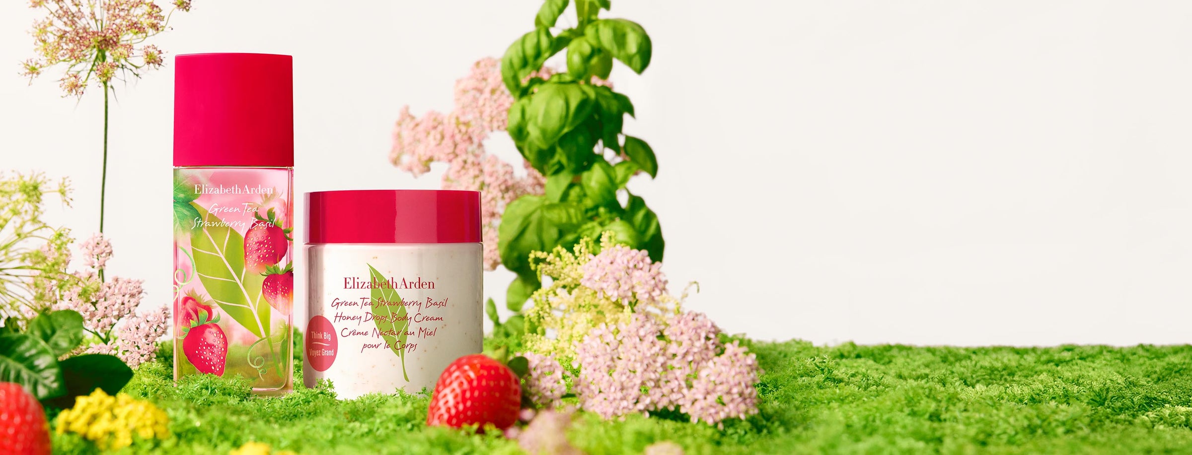 Green Tea Strawberry Basil Eau de Toilette and Honey Drops Body Cream in a cottage background with strawberries and basil. 