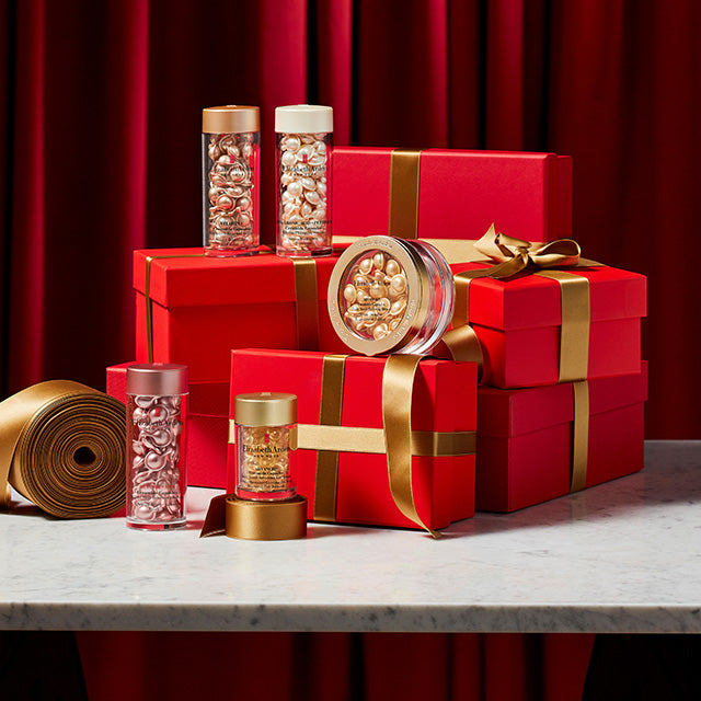 Red gift boxes with gold ribbons and decorative items on a red curtain background with Ceramide Capsules 